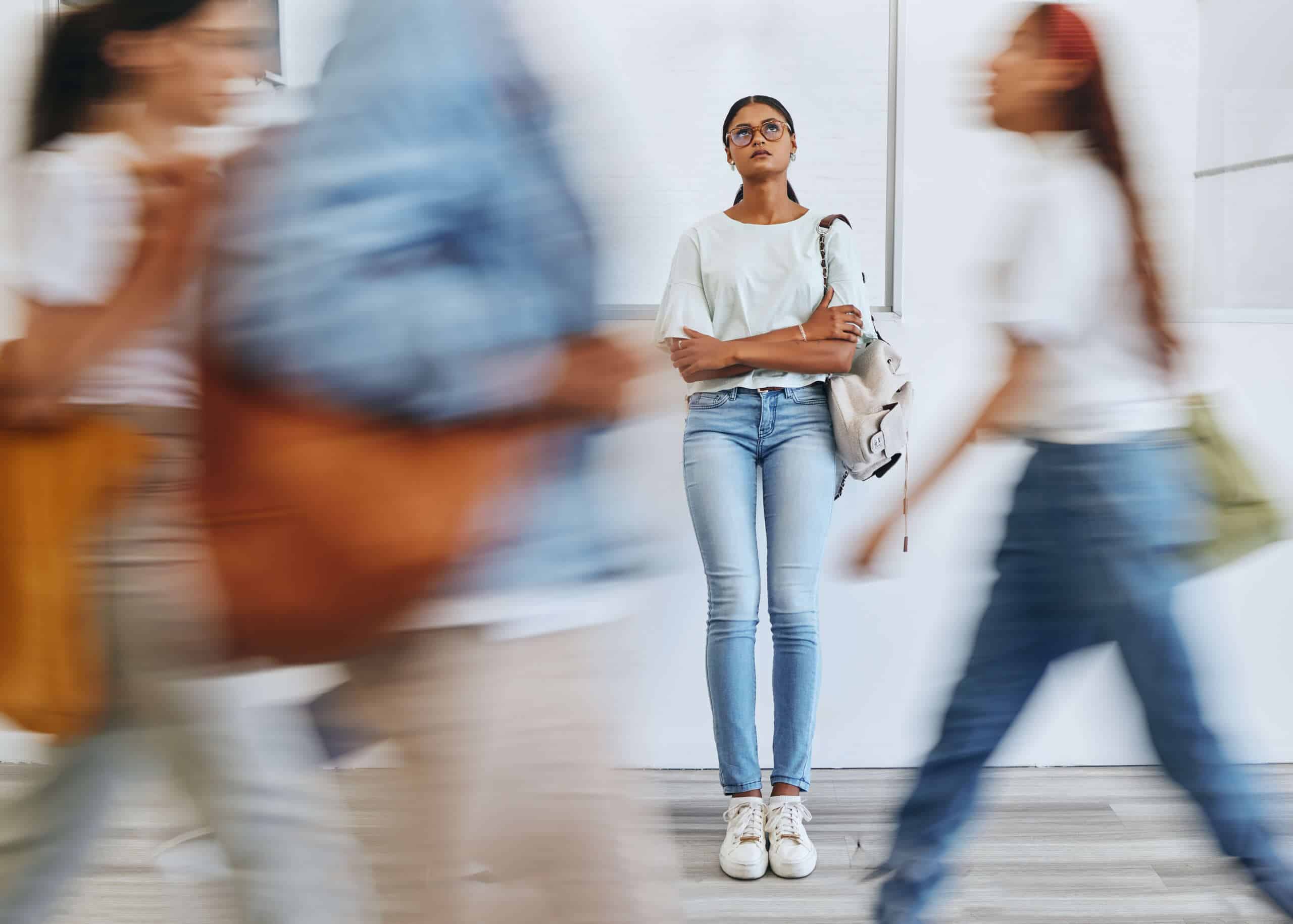 Anxiety, fear and a woman in busy crowded university sad and thinking.