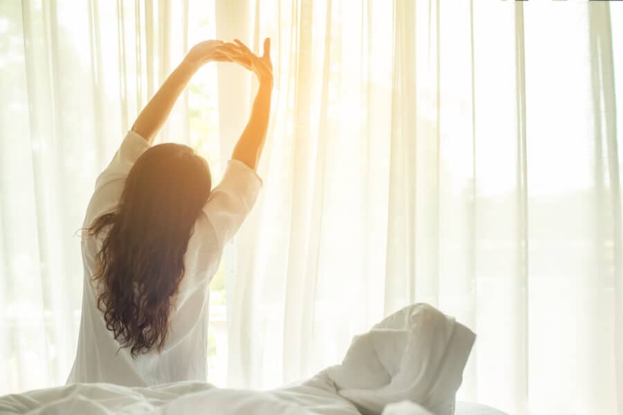 Asian women waking up stretching in bed at home, morning and sunny day. Lifestyle Concept